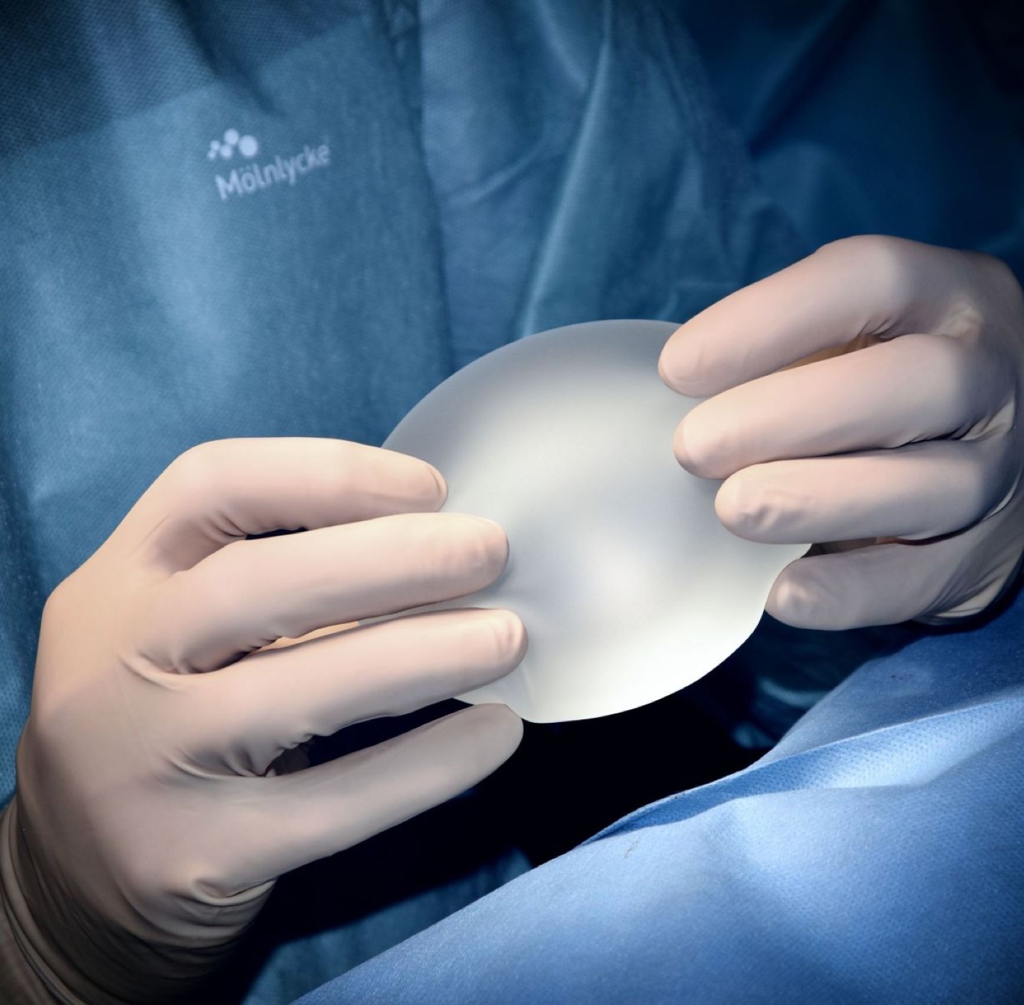 A medical professional holding a breast implant